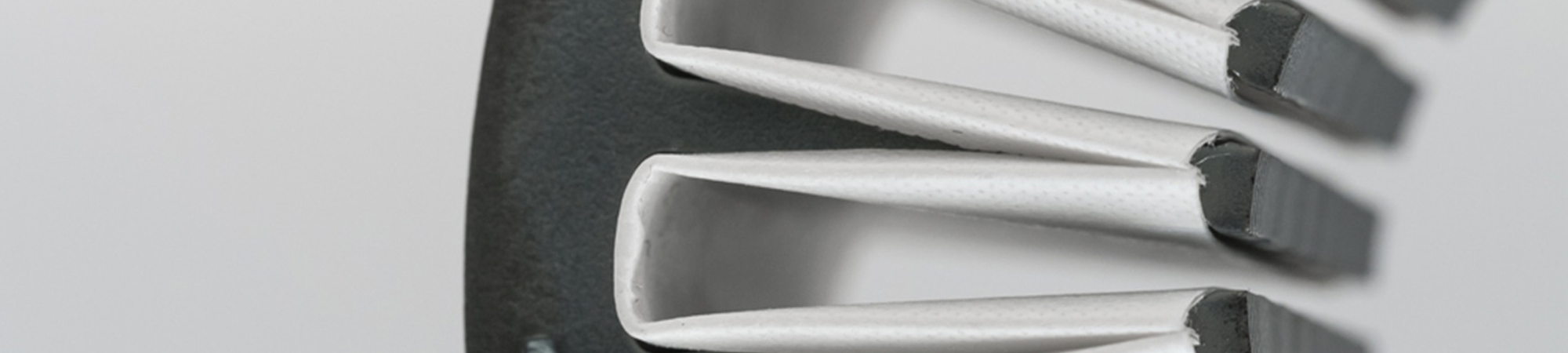 Close-up of white folded insulation liners inserted into the slots of a laminated core