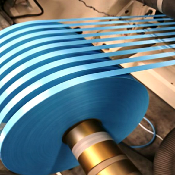 Blue film in many parallel strips running onto a wound roll with a brass core