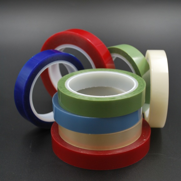 Stacked rolls of electrical adhesive tape in red, blue, green, beige and white