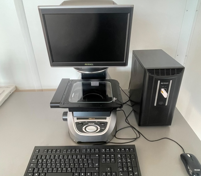 KEYENCE IM-8000 Messprojektor am Standort Leobersdorf, mit Monitor, Glas-Messtisch, Controller, Tastatur und Maus.